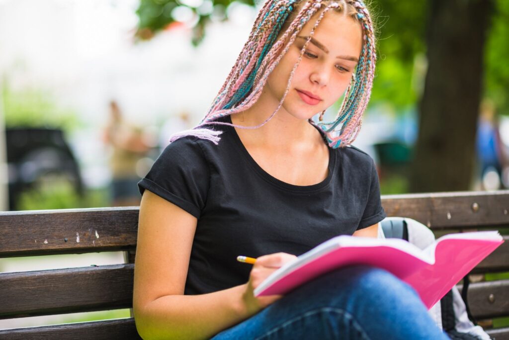 Девушка на скамейке что-то пишет в блокнот