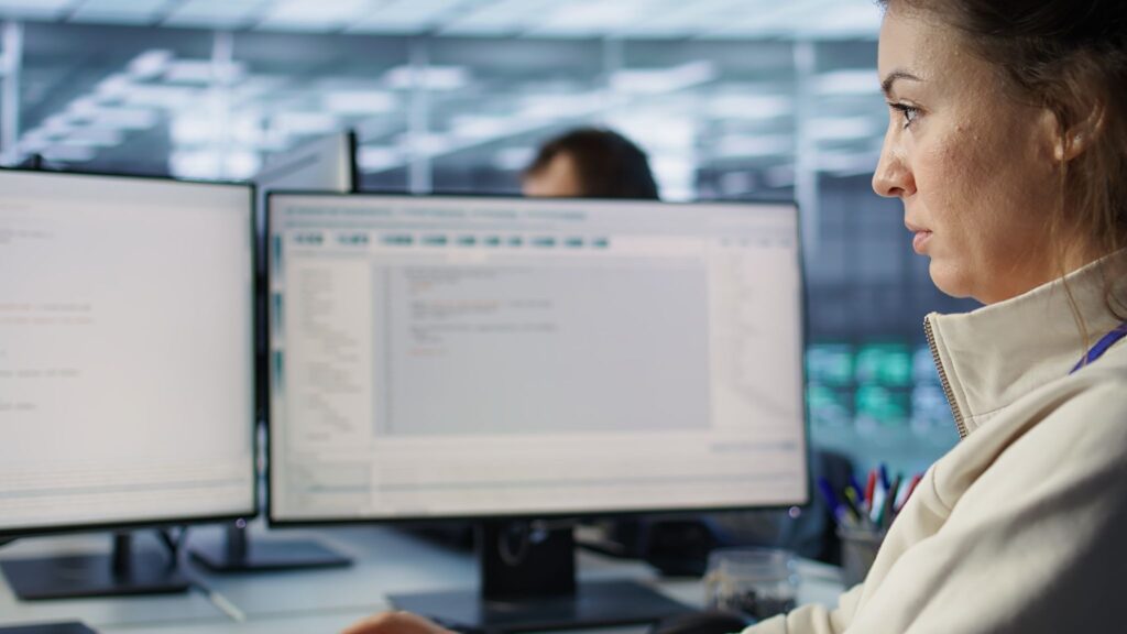 2 монитора и девушка, которая смотрит на них