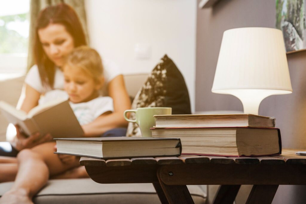 Книги, лампа, на заднем фоне мама и девочка