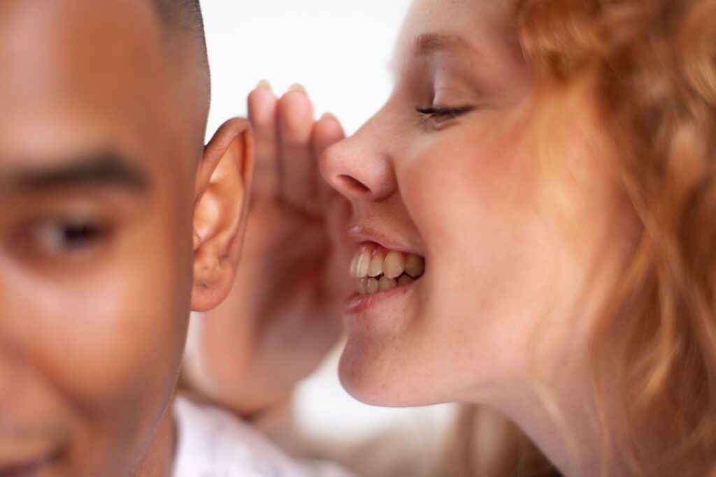 Девочка шепчет мальчику что-то на ухо