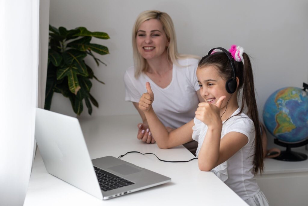 Девочка в наушниках и мама смотрят в ноутбук