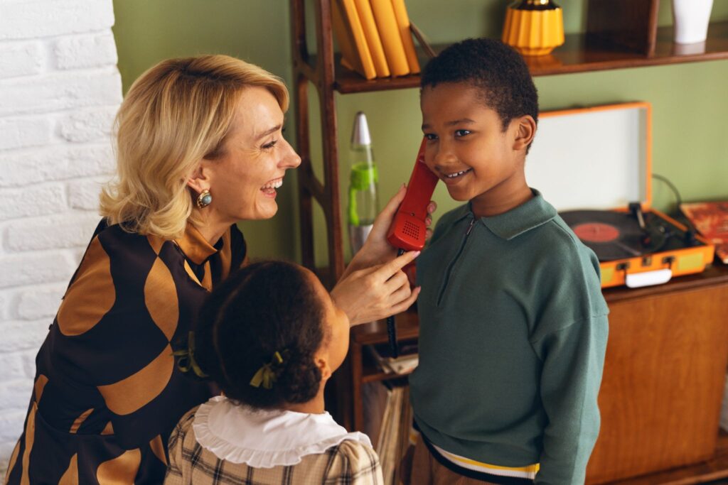 Мама протягивает телефон мальчику и рядом девочка