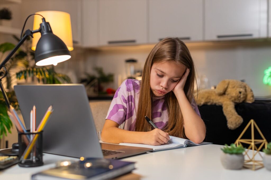 Девочка пишет в тетради за столом