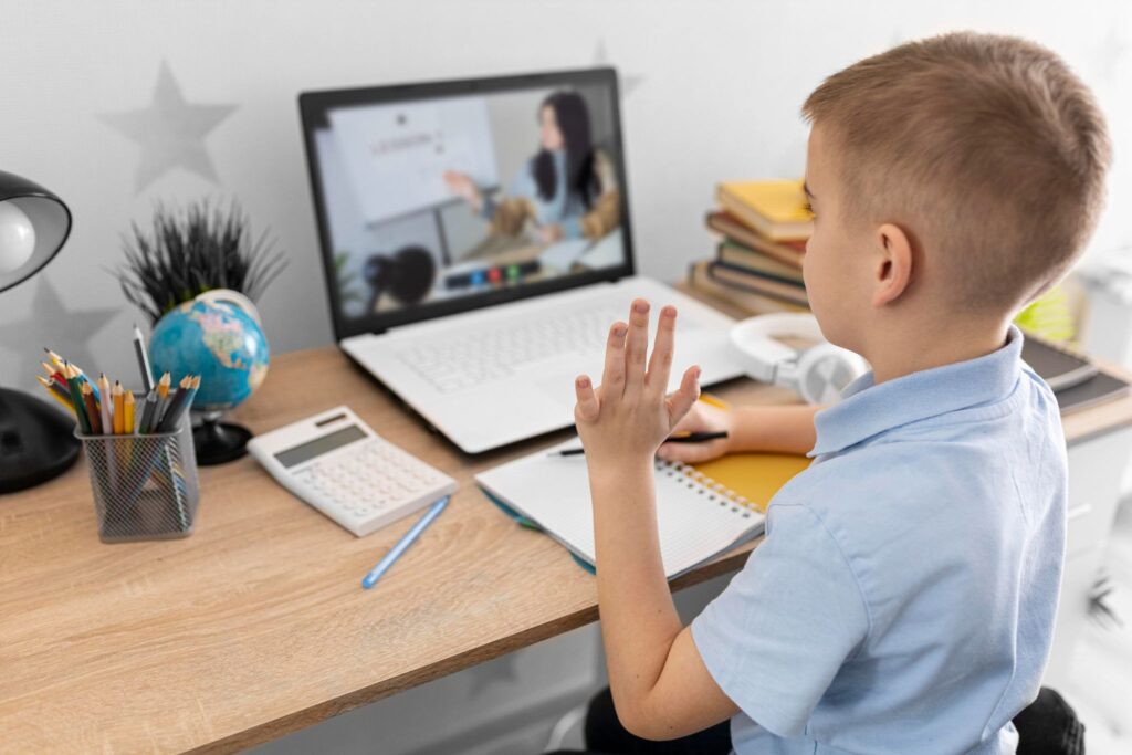 The boy is reaching out and looking at the laptop.