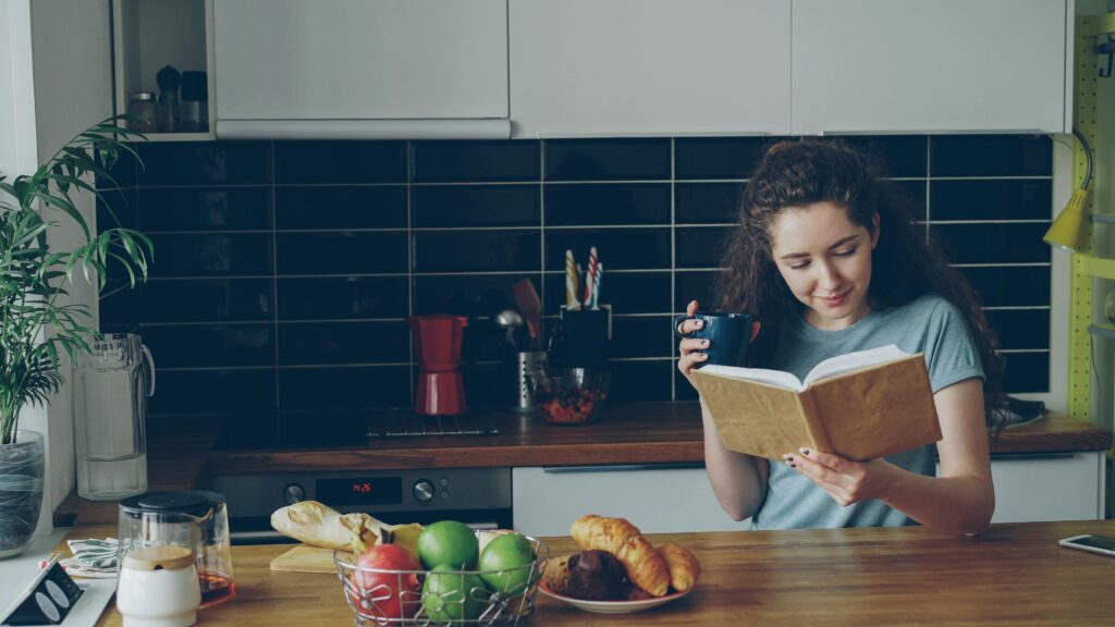 Девушка на кухне читает книгу