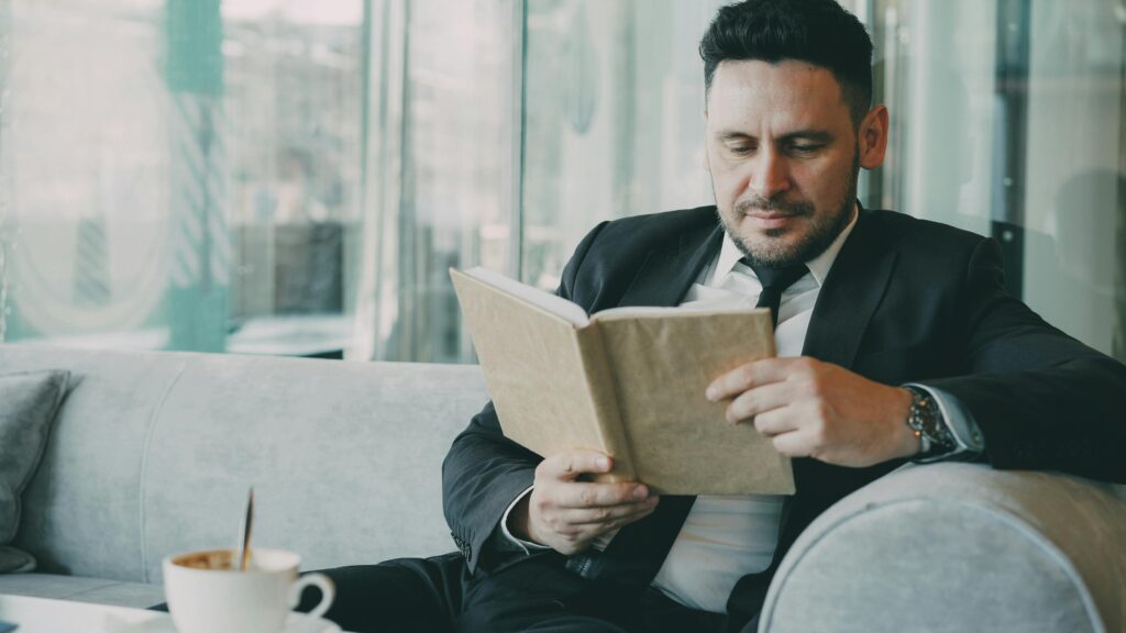 Мужчина на диване читает книгу