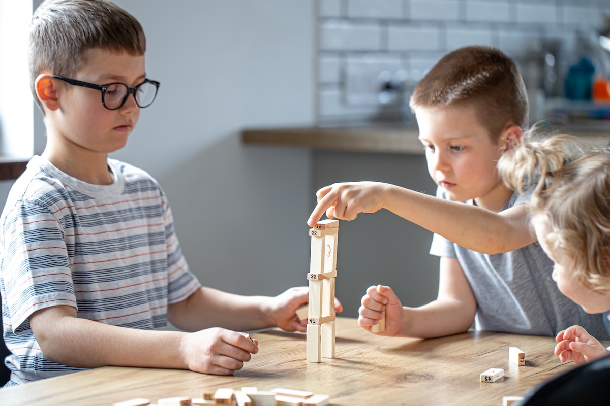 Дети играют в настольную игру с деревянными кубиками — развитие soft skills через игру