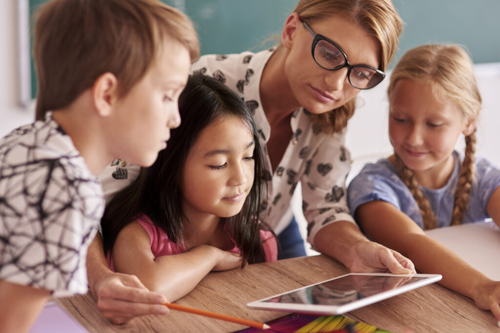A woman and 3 kids looking at a tablet