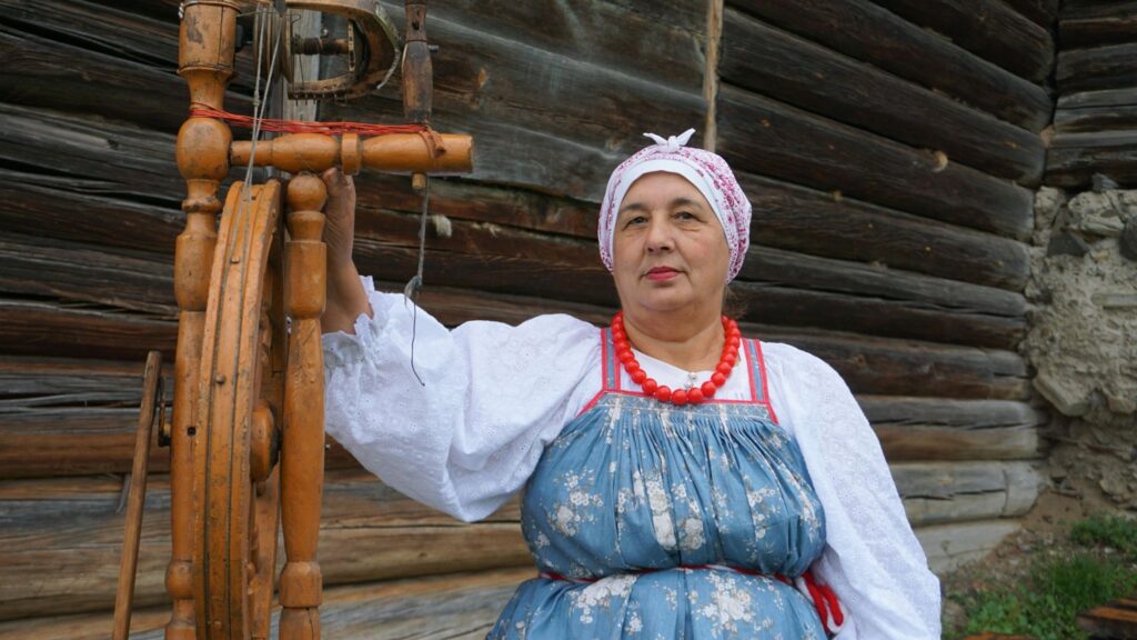 Женщина в сарафане за прялкой