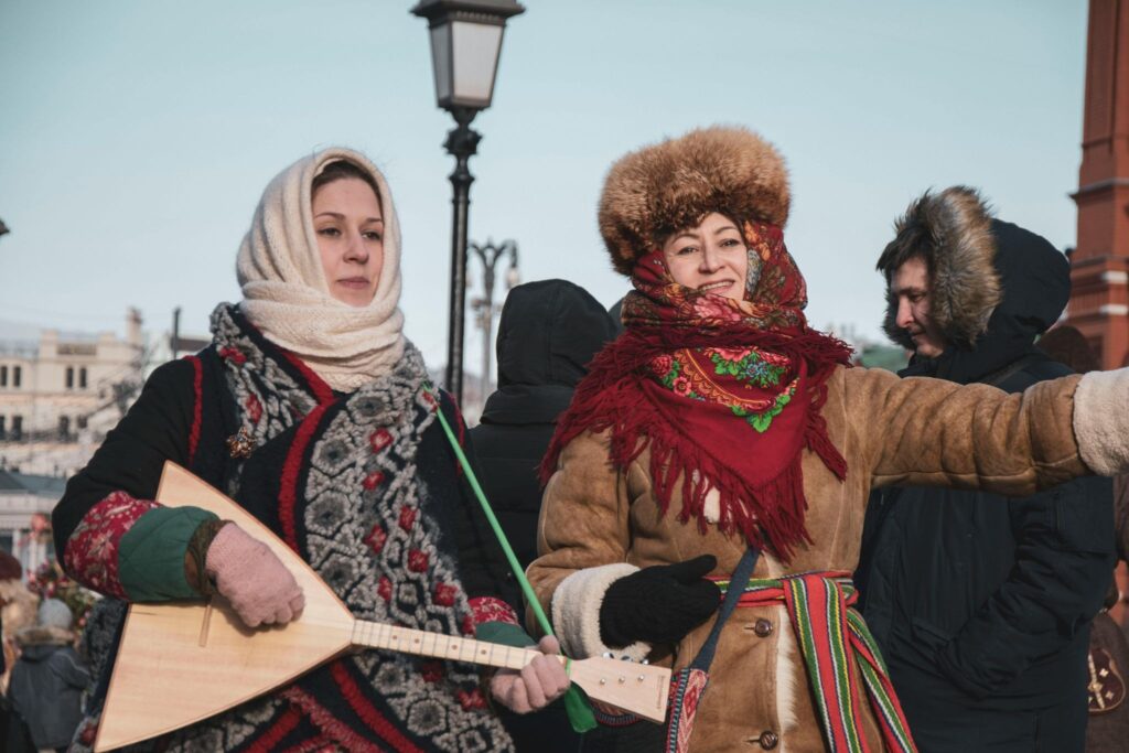 2 женщины в зимней одежде, у одной в руках балалайка