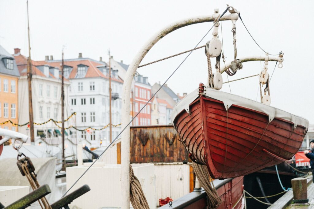 A boat is being lifted by a mechanism against a city backdrop
