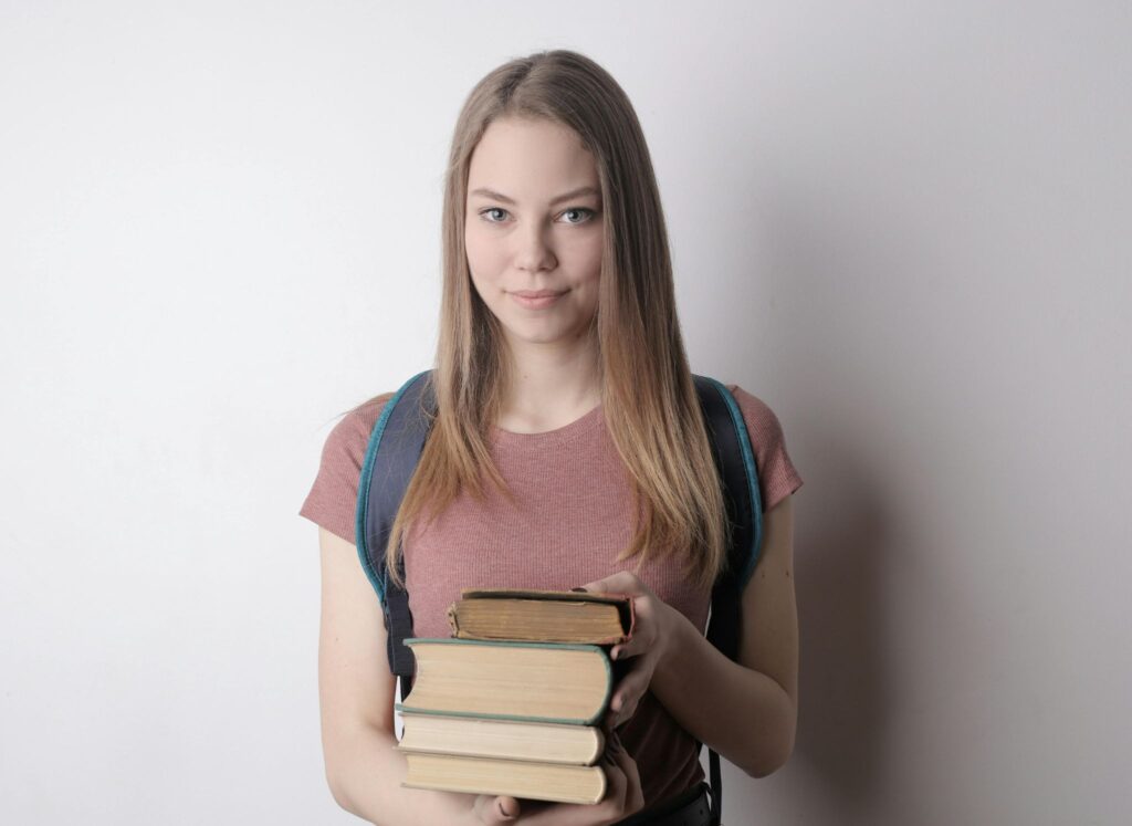 Девушка держит стопку книг