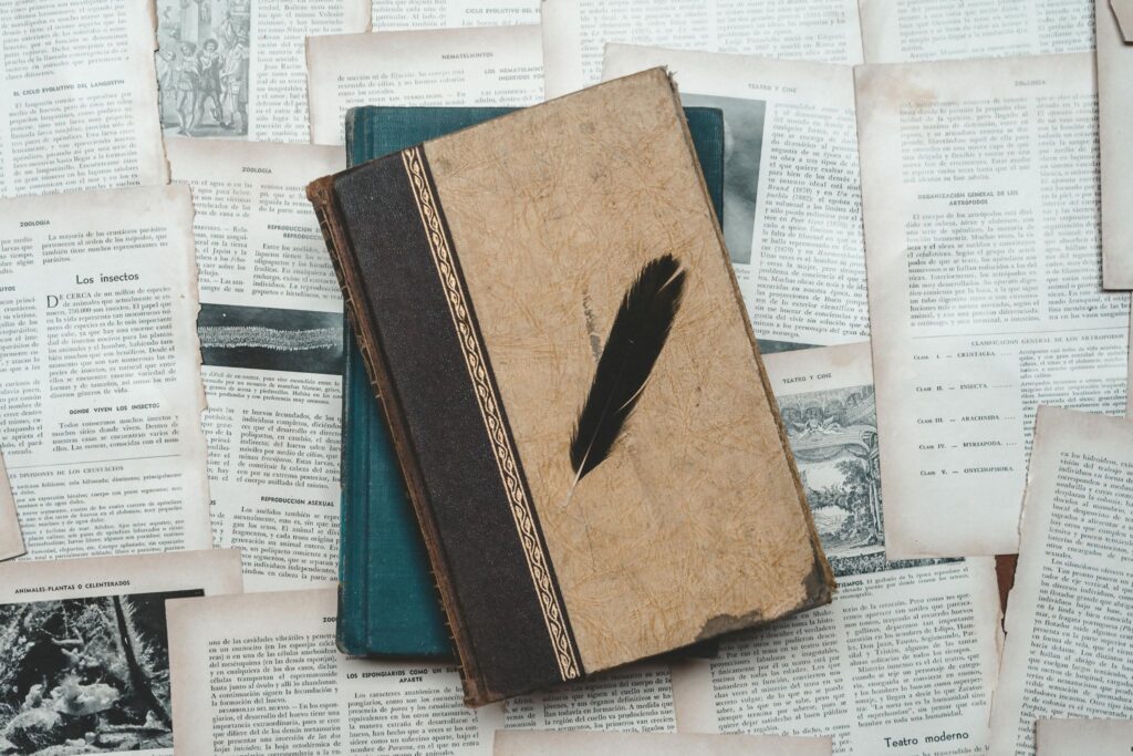 Старая книга на газетах, а на ней перо