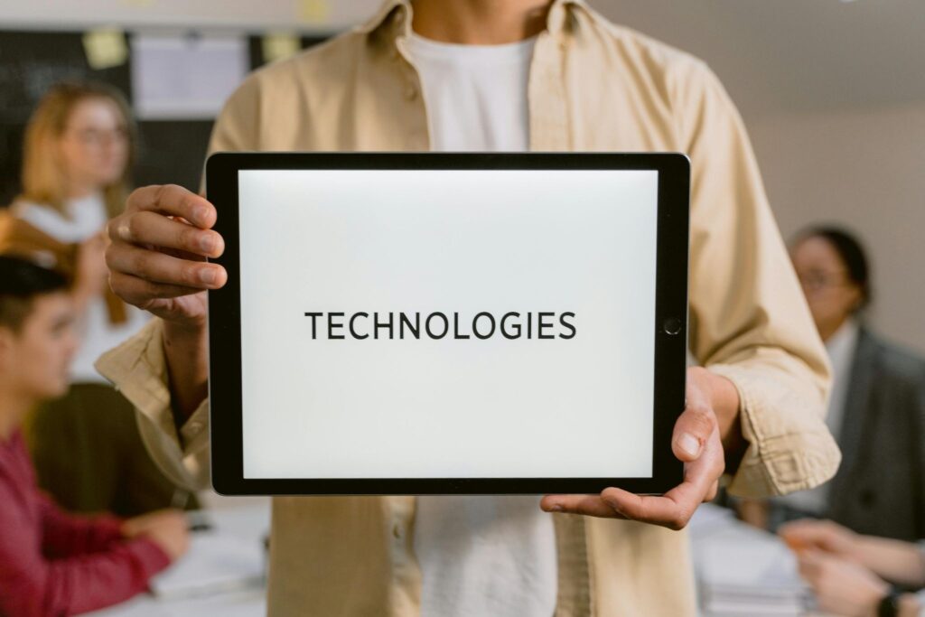 Человек держит планшет, на котором написано: TECHNOLOGIES