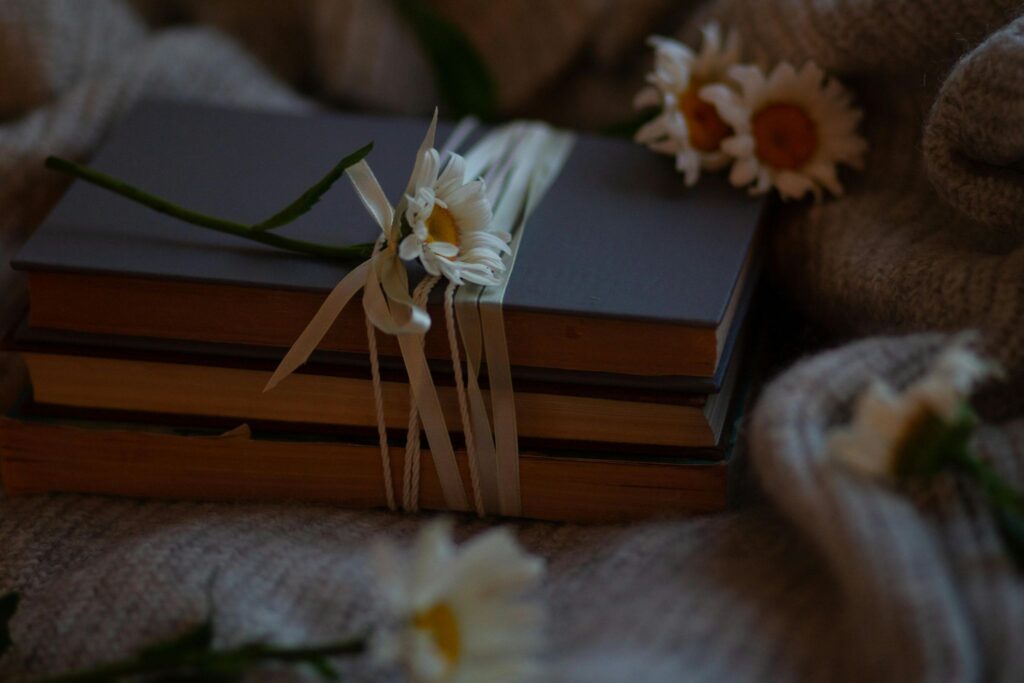 Стопка книг перевязана тесьмой и рядом ромашки