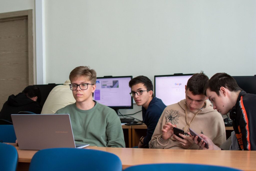Подростки в классе за ноутбуками и смартфонами, образ экрана как нормы урока