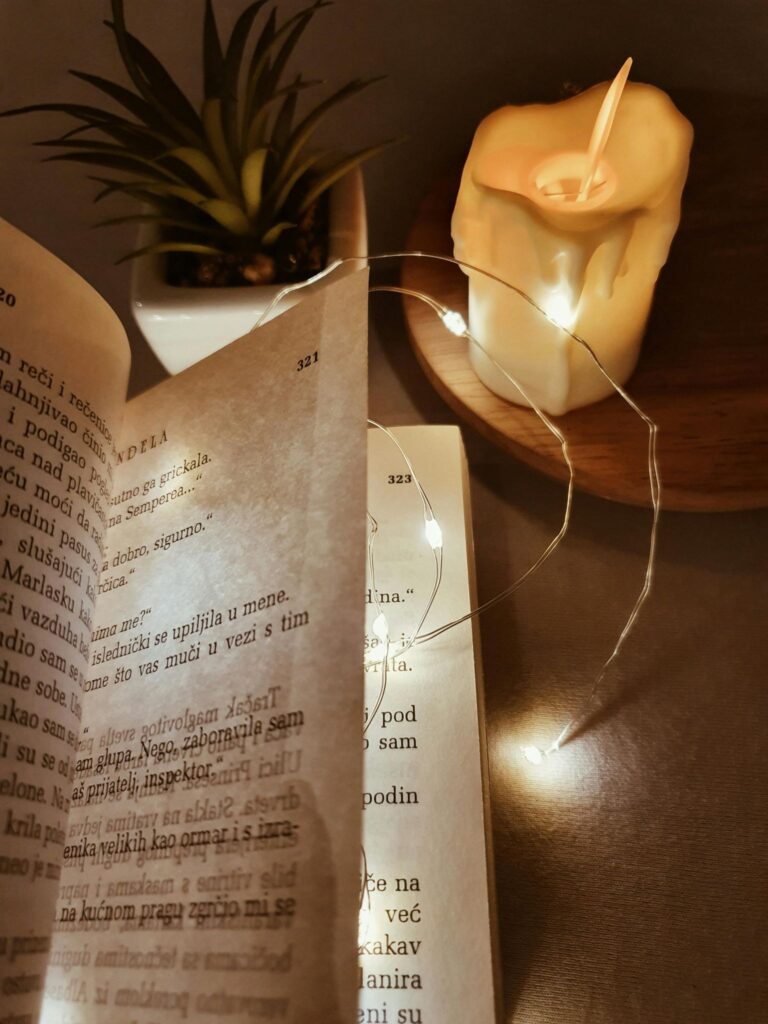 Раскрытая книга стихов на деревянном столе с гирляндой и свечой, тёплый образ вечернего чтения