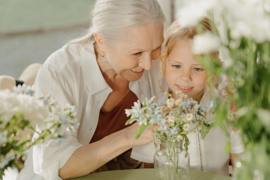 A grandmother is showing flowers to her granddaughter