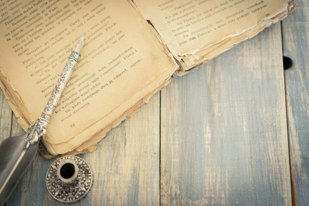 An old book and an old-fashioned pen on a wooden table
