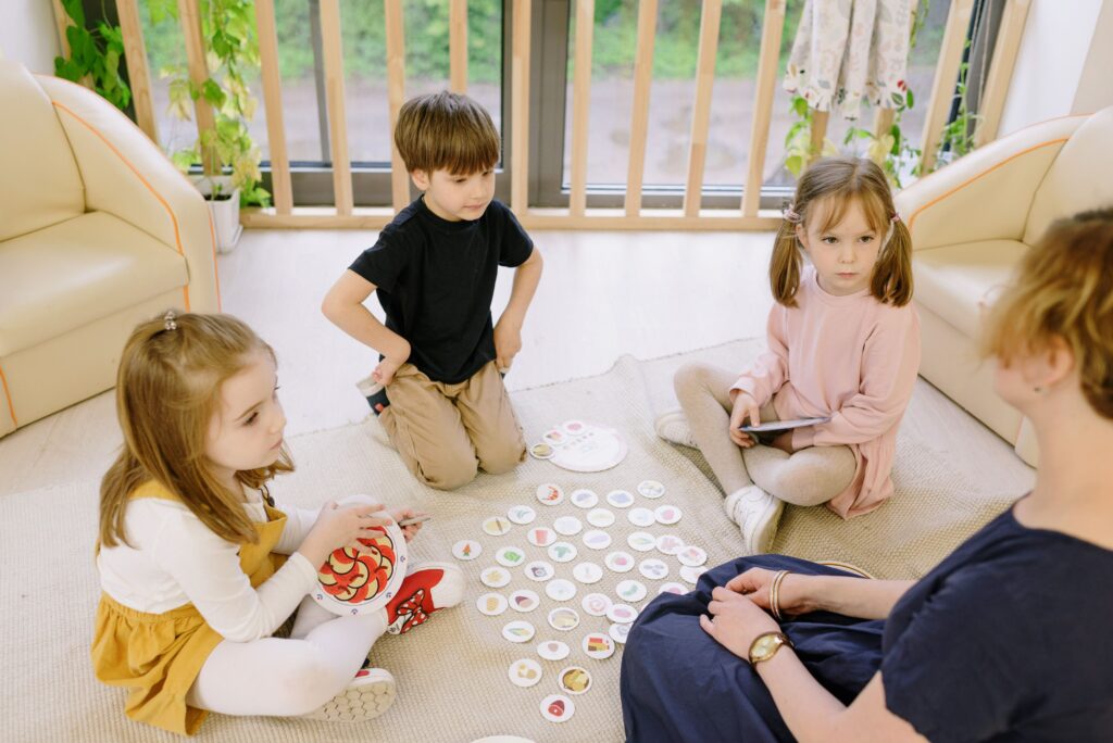 a group of three children is playing a card game with mother or teacher