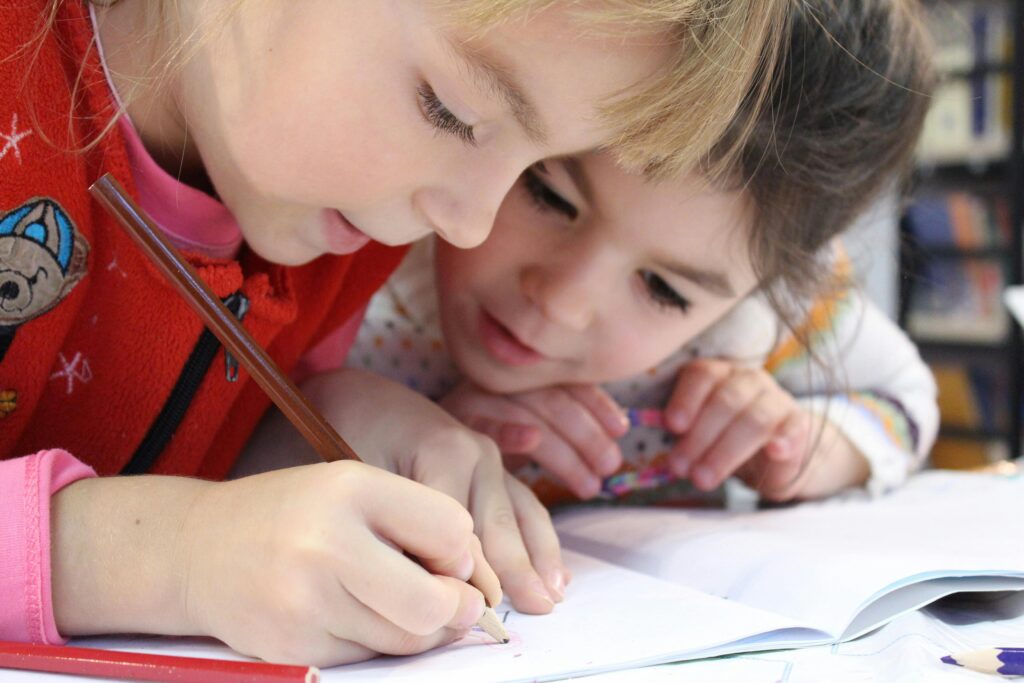 Two girls writing down something in a notebook