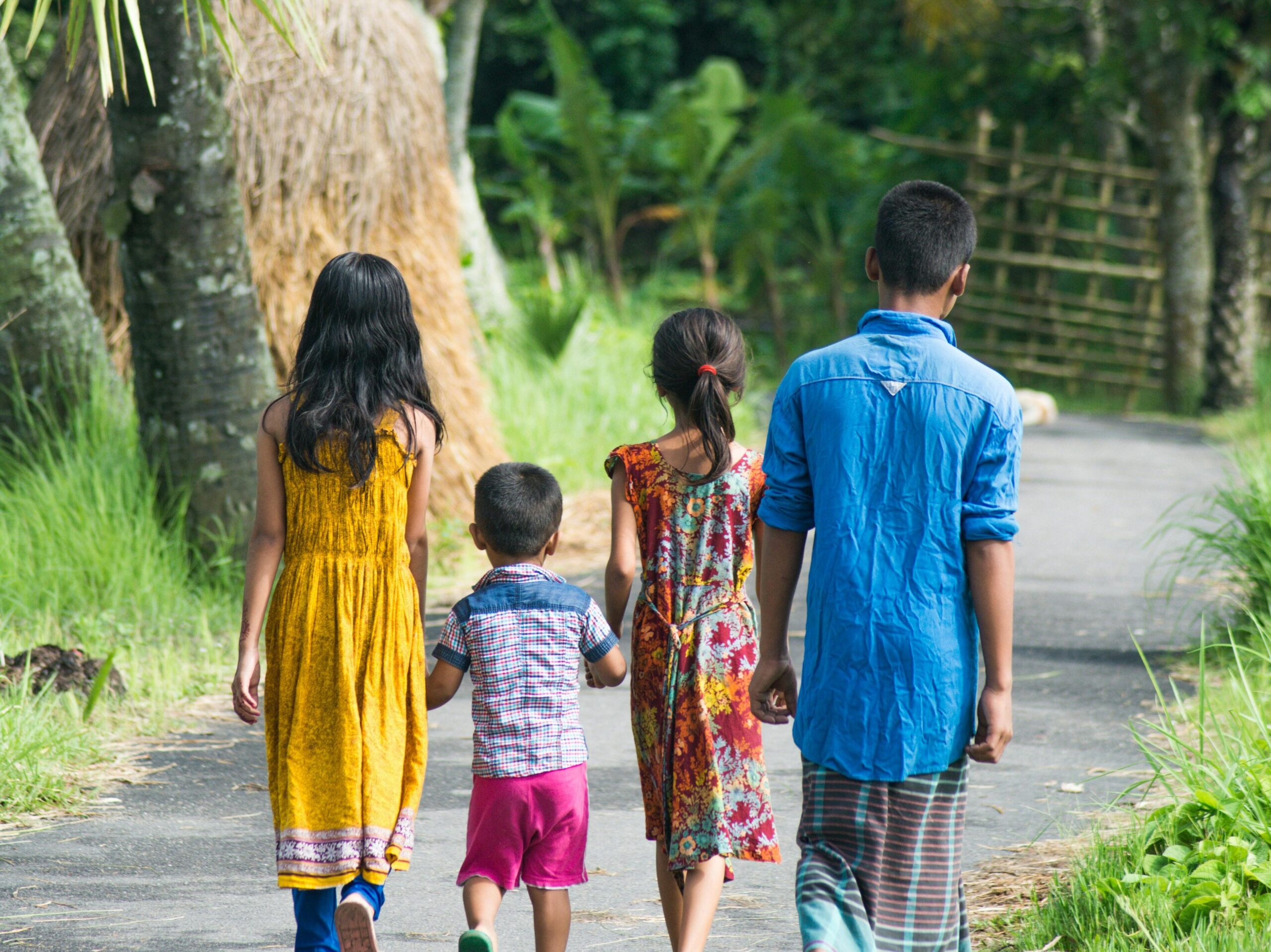A small group of children walking together outdoors, seen from behind