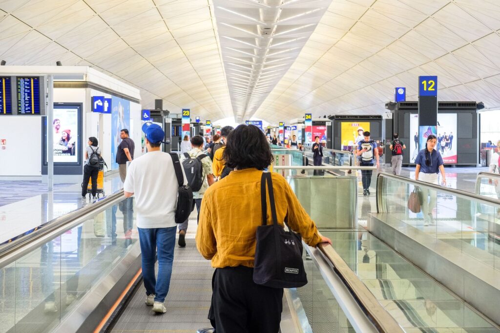 Spacious airport arrivals hall, passengers walking with suitcases
