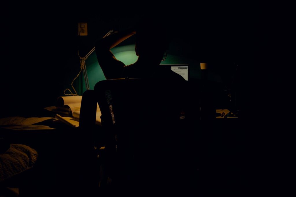 Silhouette of a person at a computer in a dark room, image of the founder