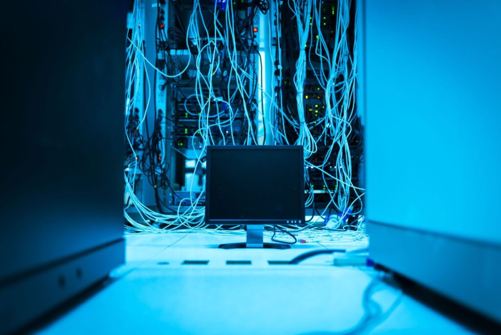Server racks and network cables in the blue lighting of a data center