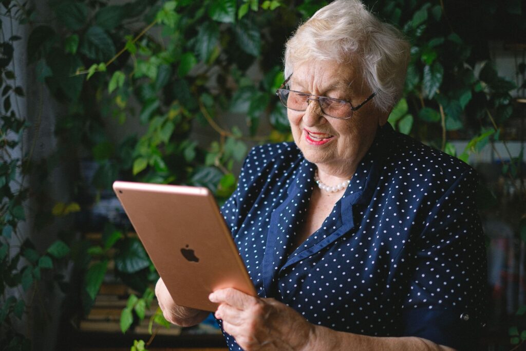 The grandmother smiles on a video call with a tablet in a bright room.
