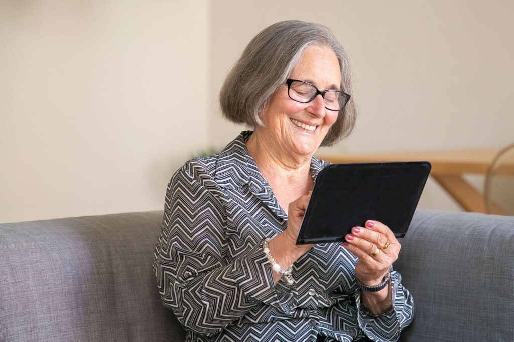 Elderly woman with a tablet at home, warm home scene