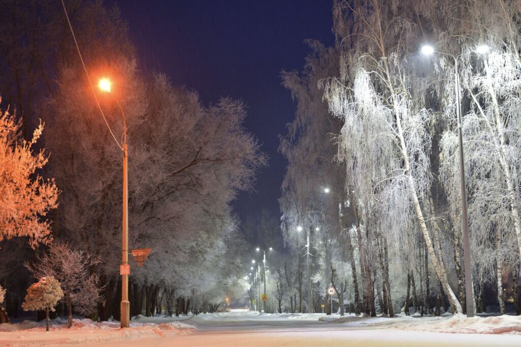 Тихая заснеженная городская улица под фонарями ночью
