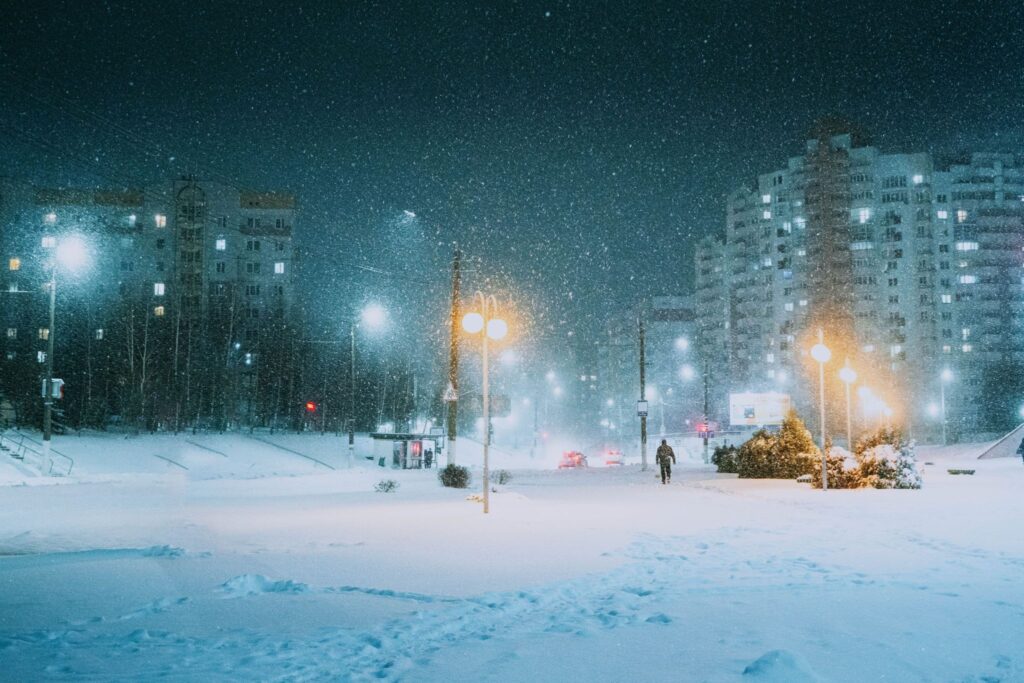 Snowy city street under streetlights at night