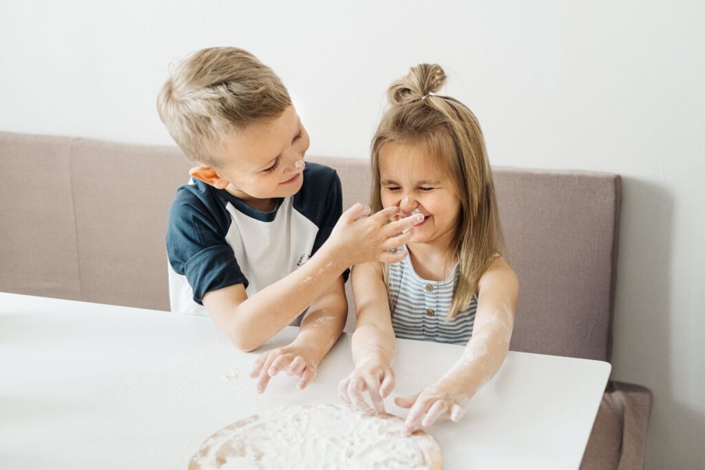 Дети со смехом играют с мукой на кухне