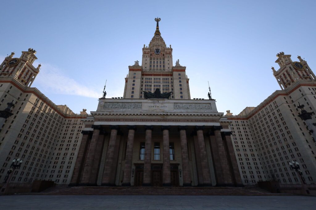 Высотное здание со шпилем снизу вверх, каменный фасад с колоннами