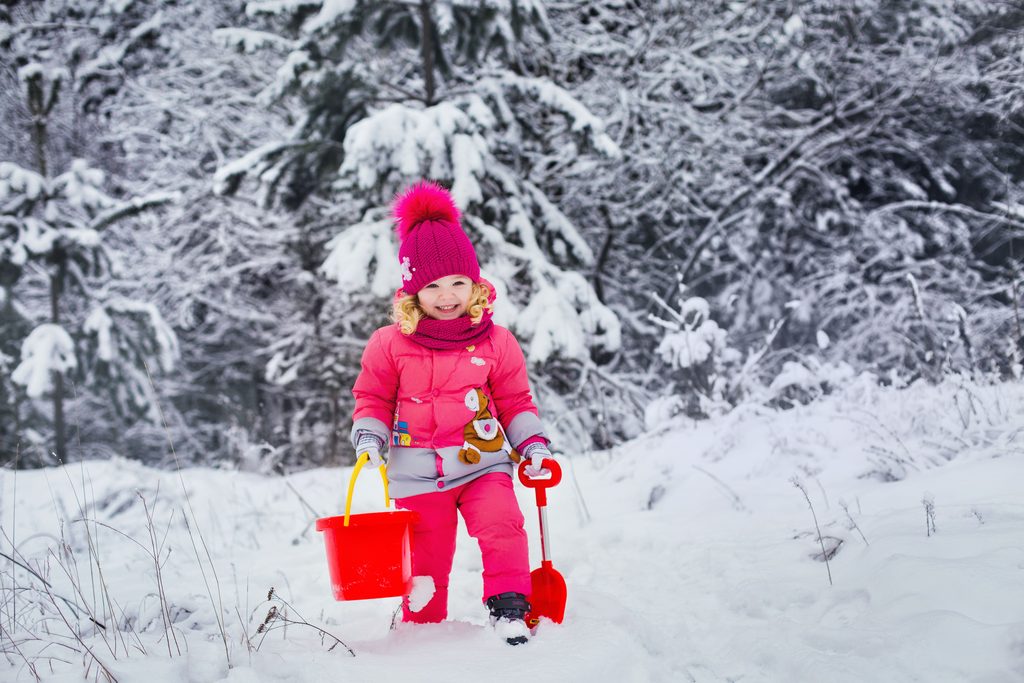 A child in winter clothes is playing in the snow outside