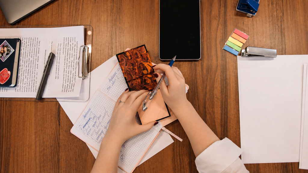 An adult writing notes at a kitchen table