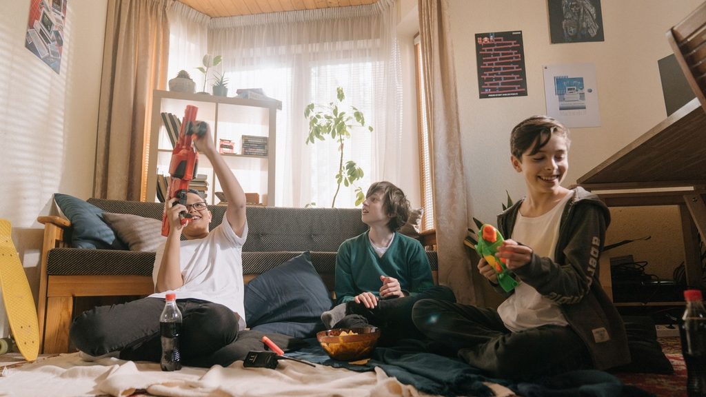 Three siblings of different ages busy with different tasks in one room