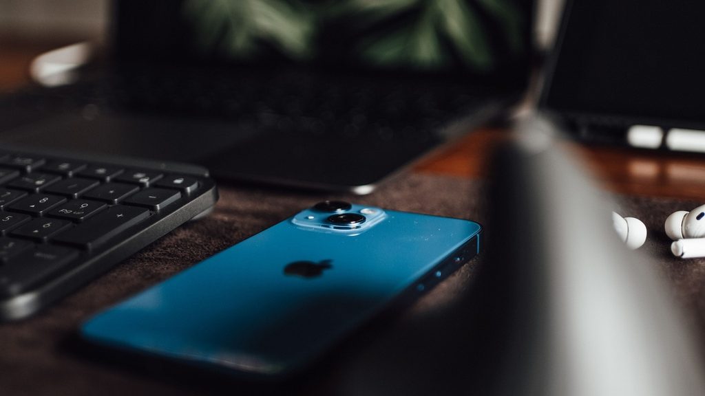 A child at a laptop in the evening with a phone face down on the table