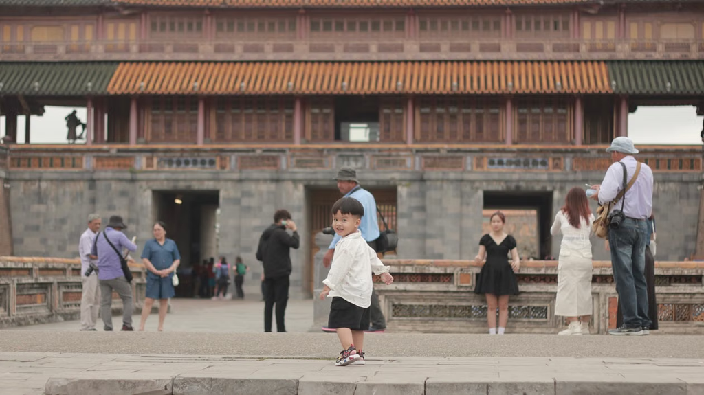A little boy is running up the stairs toward a pagoda.