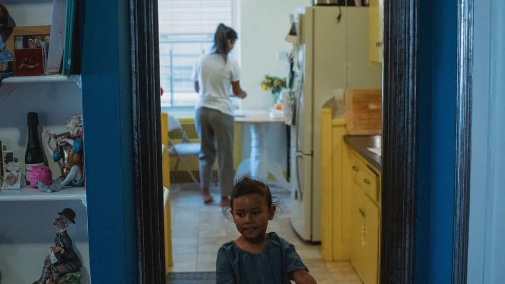 An adult speaking to a child standing in a kitchen doorway