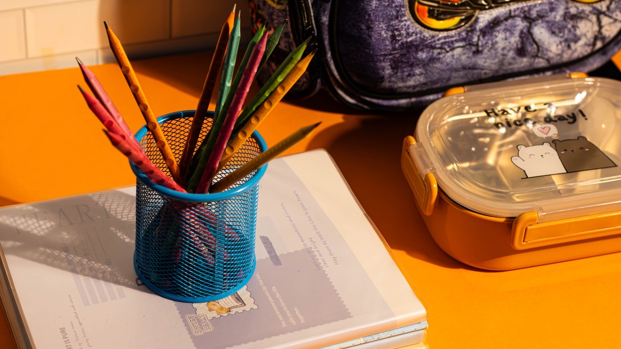 A child's desk with notebooks, pencils in a jar, and a pinned note
