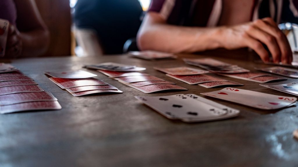 Two people playing a card game at a kitchen table